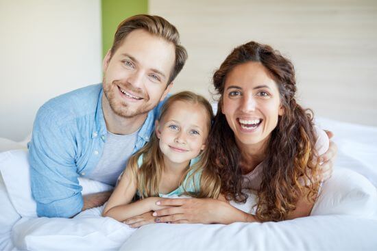 família deitada na cama limpeza e higienização de cochão